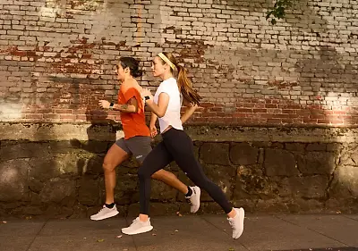 Man and woman running on a street in a pair of HOKA running shoes