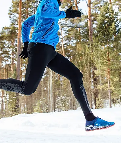 Close up of running pants and shoes as runner runs through the snow