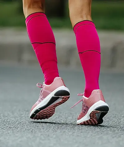 Close up of woman's pink compression socks and shoes as she runs.