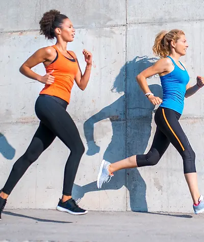 Side view of two women running on road